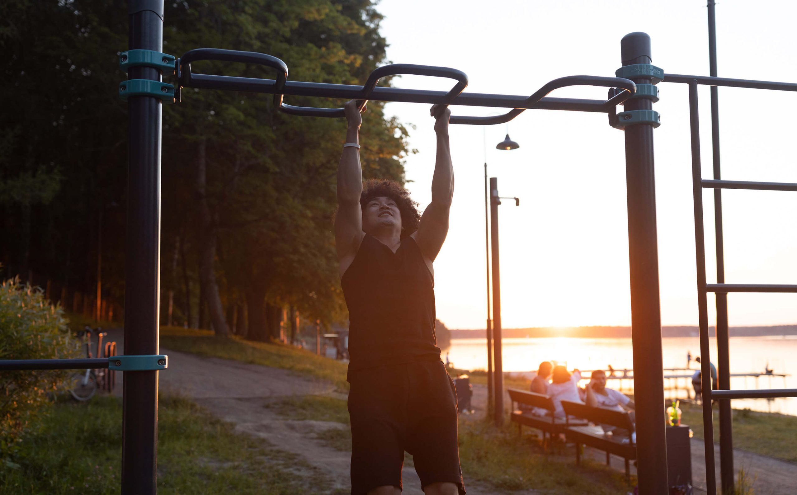 A man doing pull ups using an outdoor gym equipment.