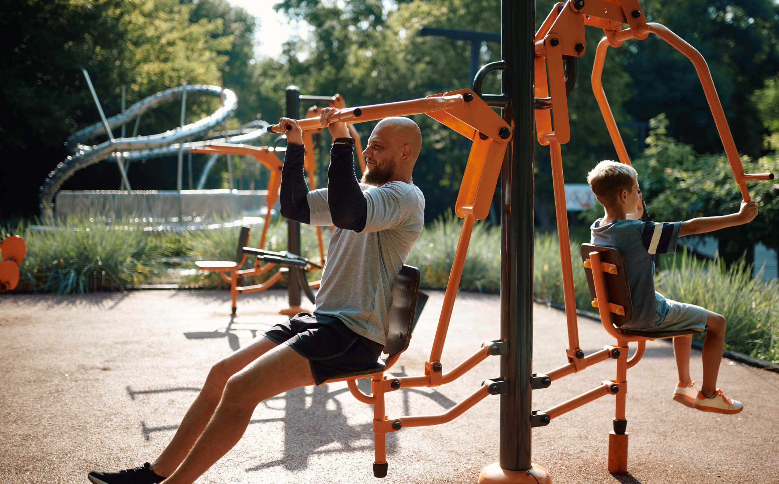 A man and child using an outdoor gym equipment.