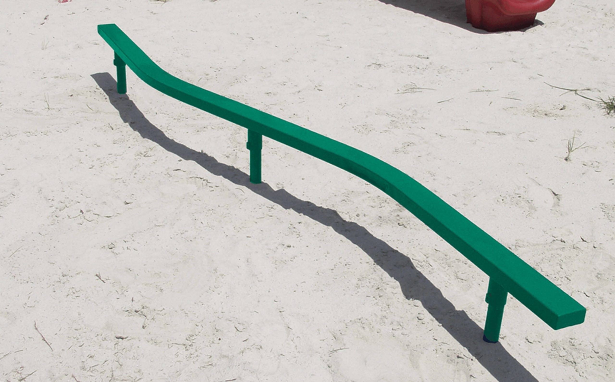 A green balance beam in the middle of a park.