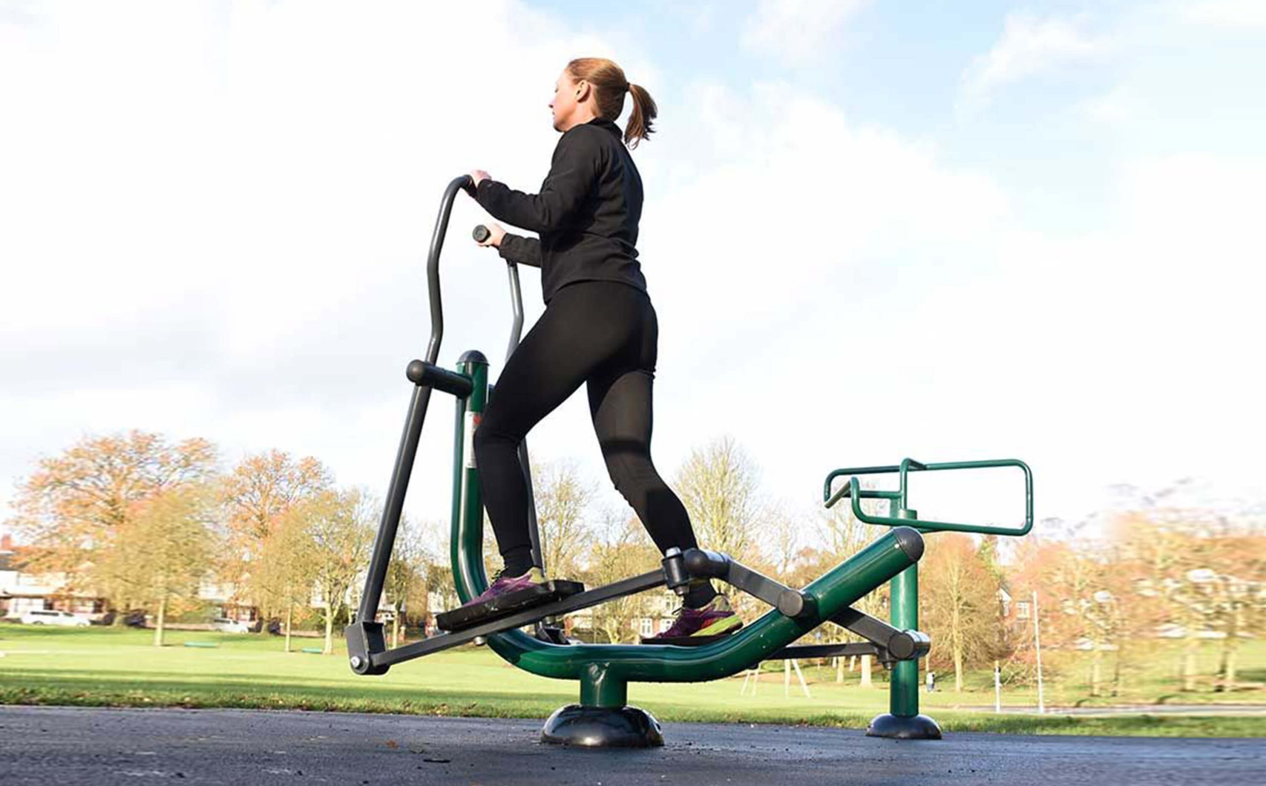 A woman exercising outdoor, using a glider.