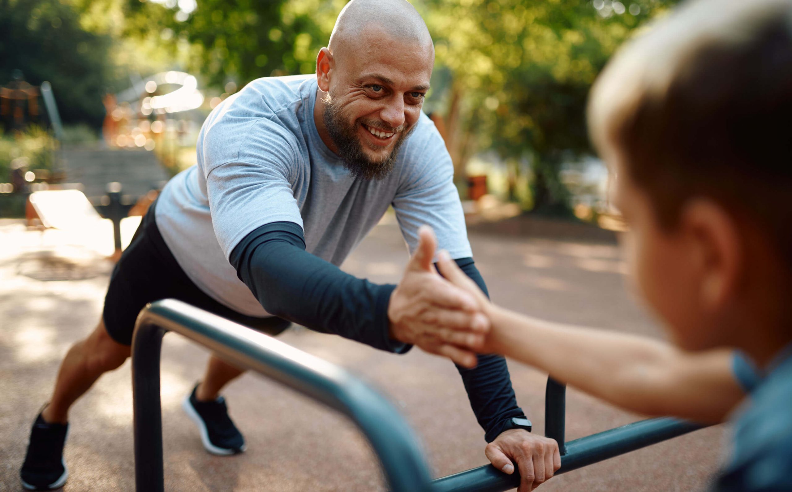 An adult and child exercising outdoors together.
