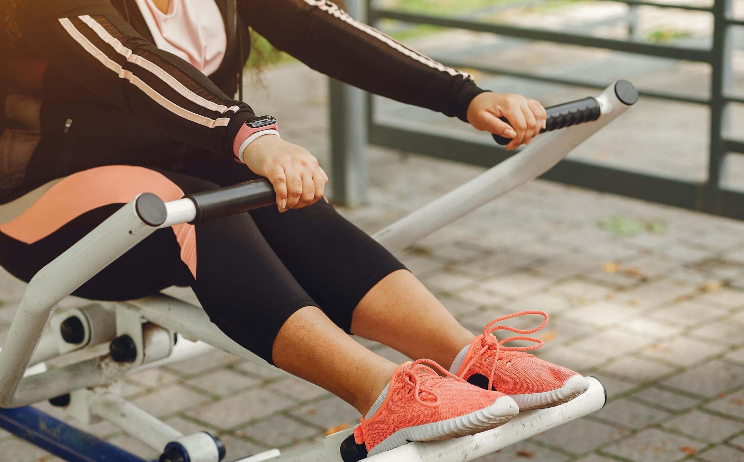 A woman is exercising outdoor, using an outdoor gym equipment. 