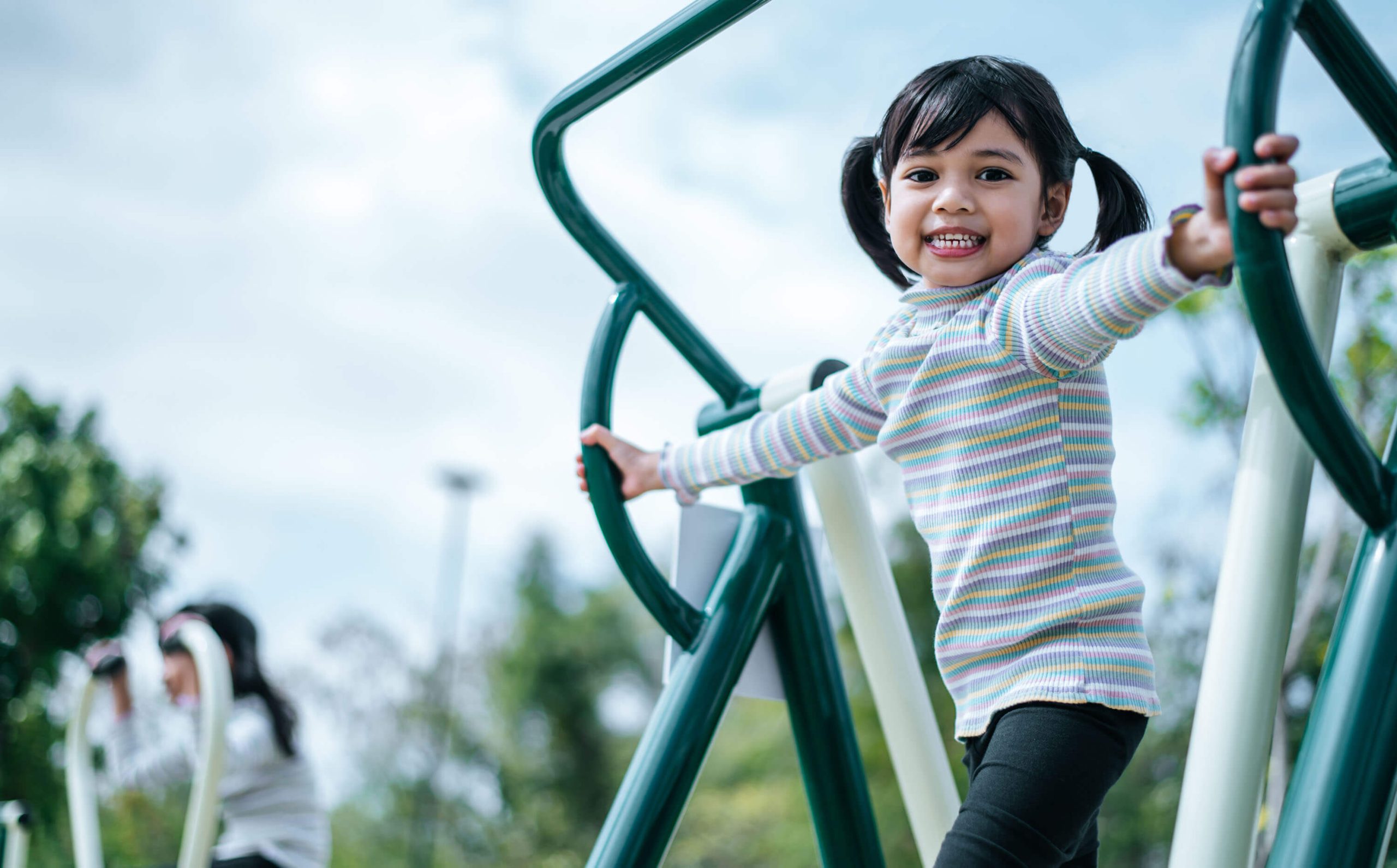 A cheerful girl using an outdoor gym equipment. 