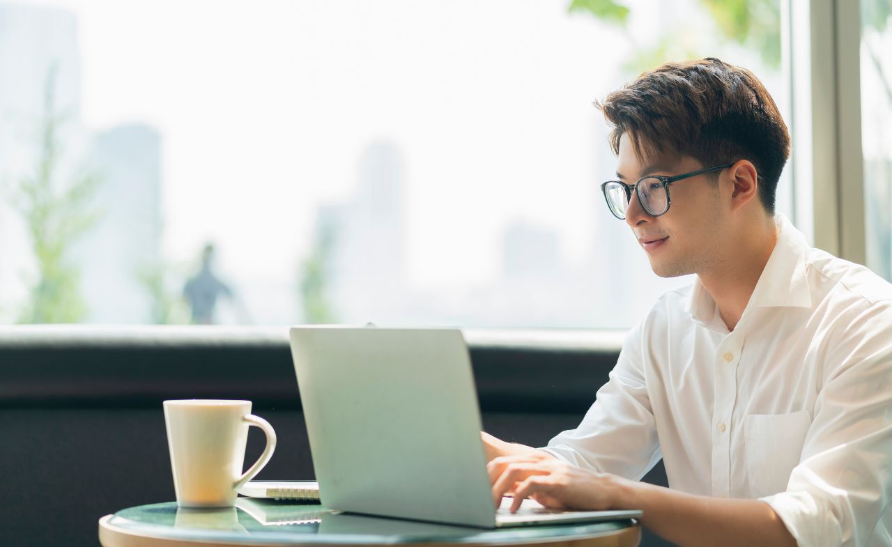 A man surfing through the web using a laptop, sitting on a desk.