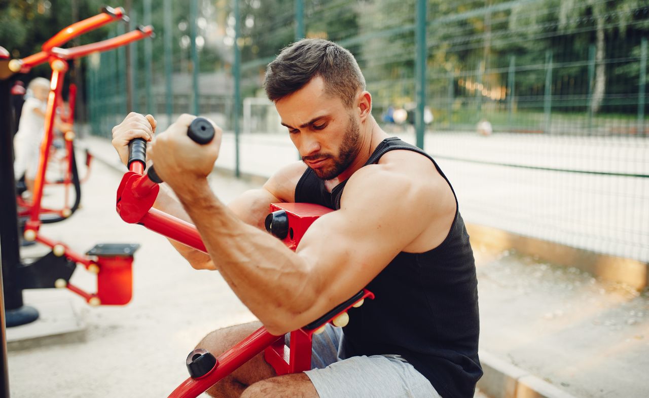 A man using arm strength equipment at an outdoor gym.