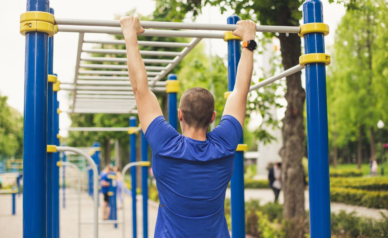 A man swinging from a monkey bar.