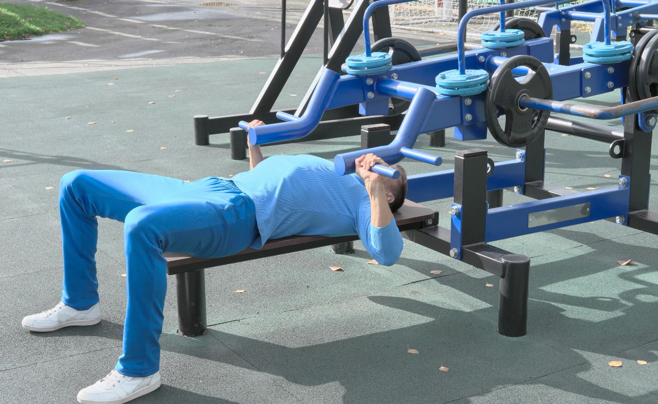A man exercises by using a chest press and pull-down machine.
