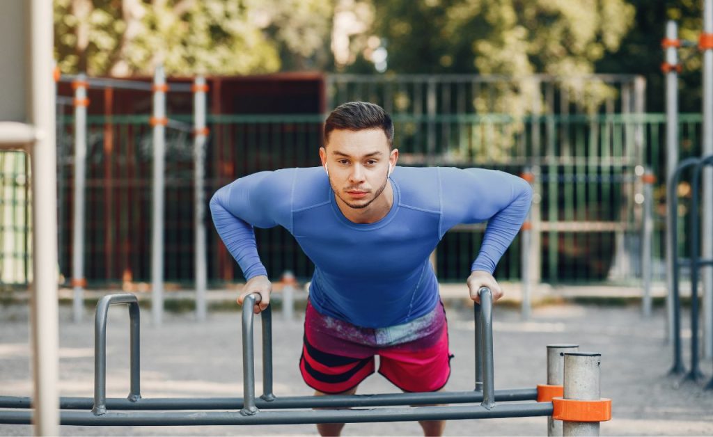 A man performing push-ups by using a balance beam.